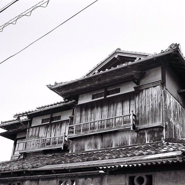 architecture, built structure, building exterior, clear sky, low angle view, roof, house, residential structure, residential building, building, window, cable, day, sky, copy space, outdoors, no people, power line, high section, city