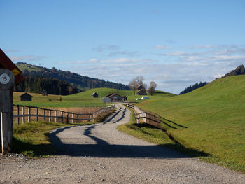 Road amidst green landscape against sky