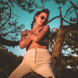 Low angle view of woman wearing sunglasses against trees