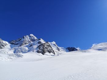 Scenic view of snowcapped mountains against clear blue sky