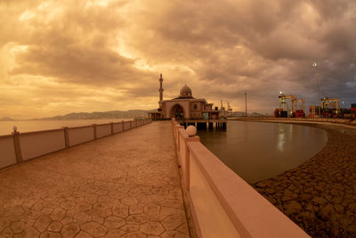 Footpath by sea against sky during sunset