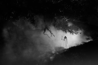 Woman standing in forest during foggy weather