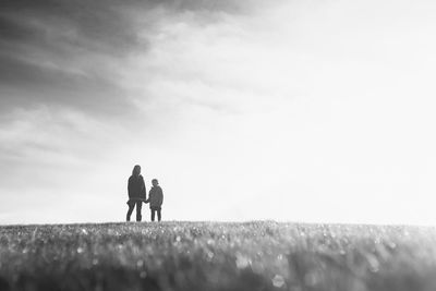 Rear view of couple standing on field against sky