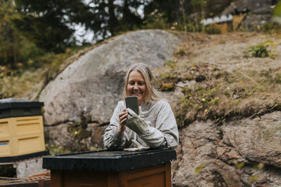 Female beekeeper using cell phone