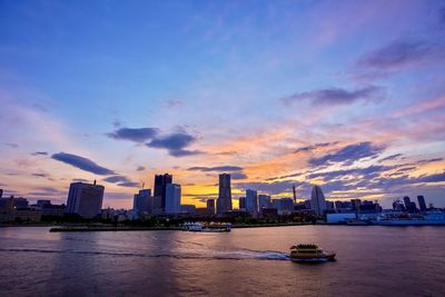 Boats in river against sky during sunset