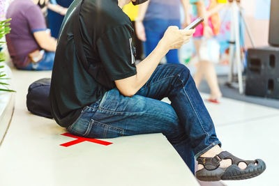 Low section of man sitting on mobile phone