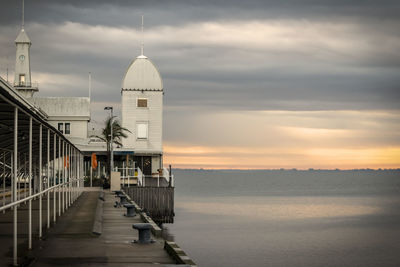 Building by sea against sky during sunset