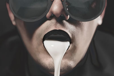 White liquid spilling from man mouth