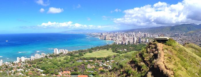 High angle view of city by sea against blue sky