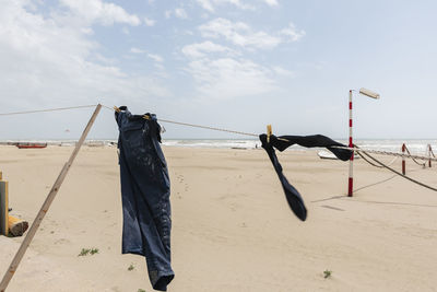 Clothes drying on clothesline at beach against sky