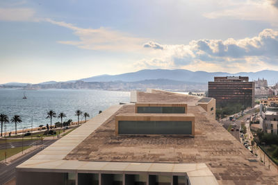 View of buildings by sea against cloudy sky