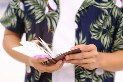 Midsection of man holding passport and tickets at airport