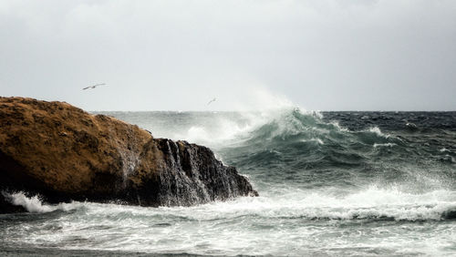 Waves splashing on sea against sky