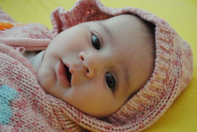 Cute baby girl wearing knitted warm clothing lying on bed