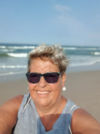 Portrait of man wearing sunglasses on beach against sky