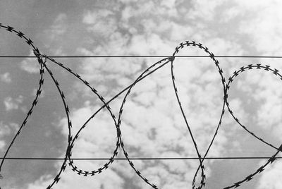 Low angle view of barbed wire against sky