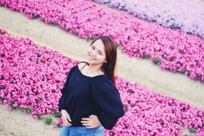 Portrait of smiling young woman standing on pink flowers