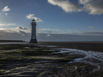 Lighthouse by sea against sky