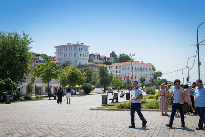 People walking on street in city against clear sky