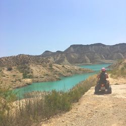 Rear view of friends riding quadbike on mountain