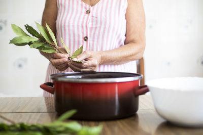 Woman using laurel for cooking in kitchen