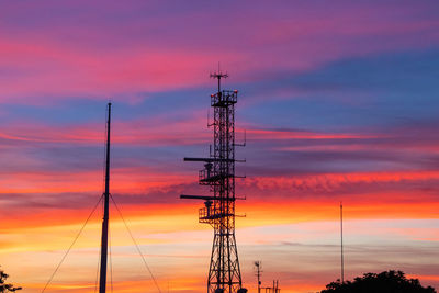 Low angle view of silhouette communications tower against sky during sunset