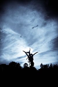 Low angle view of silhouette trees against cloudy sky