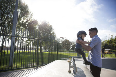 Side view of father and son at skateboard park