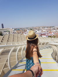 Cropped image of man holding hands with girlfriend on steps against clear blue sky