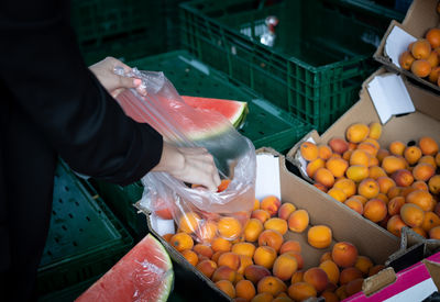 A girl buys apricots in a vegetable boutique on the market.