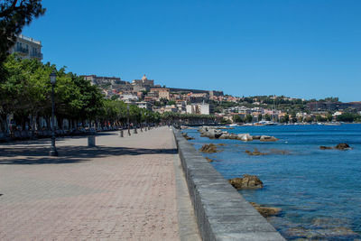 View of town by sea against clear blue sky