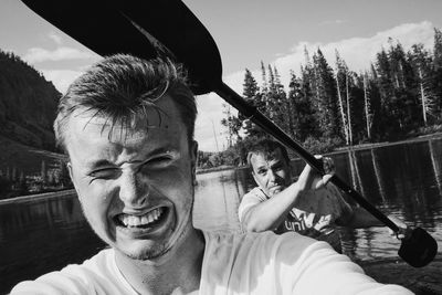 Portrait of friends sailing on boat in river against sky