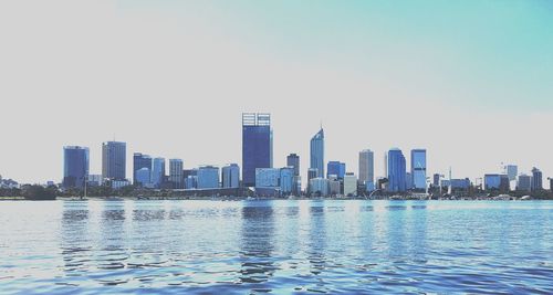 City at waterfront against clear sky