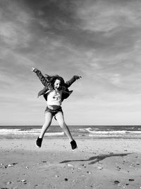 Full length of girl jumping on beach against sky