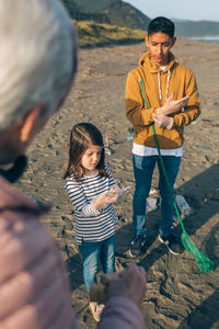 People putting on protective glove while standing at beach