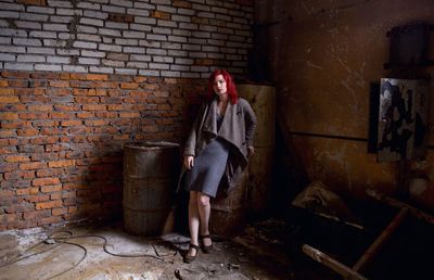 Full length of woman standing against brick wall