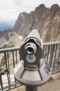 Close-up of coin-operated binoculars against mountain range
