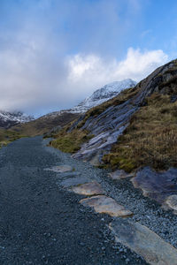 Scenic view of road by mountains against sky