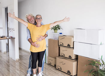 Happy couple standing against wall at home