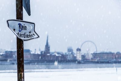 Road sign on snow covered field seen through glass