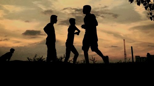 Silhouette of men against sky during sunset