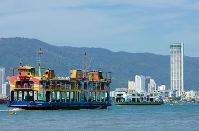 Boats in sea by harbor against sky