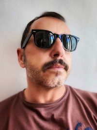 Portrait of mid adult man wearing sunglasses against wall