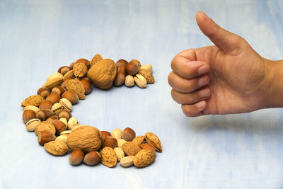 Cropped hand of man gesturing thumbs up with dried fruits on table