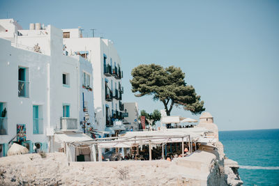 Buildings by sea against clear sky