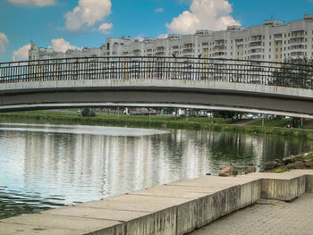 Bridge over river in city against sky