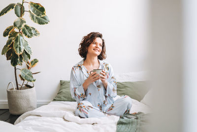 Portrait of young woman sitting on bed at home