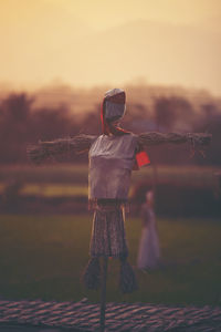 Scarecrow on field during sunset