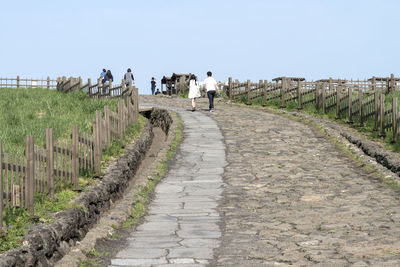 Rear view of people walking on footpath against sky at sangumburi crater