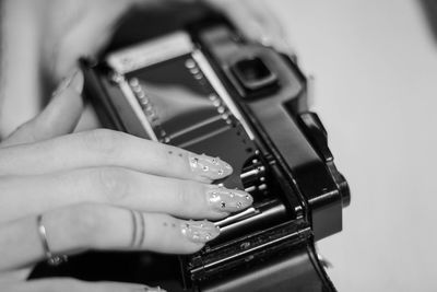 Cropped hand of woman touching vintage camera on table